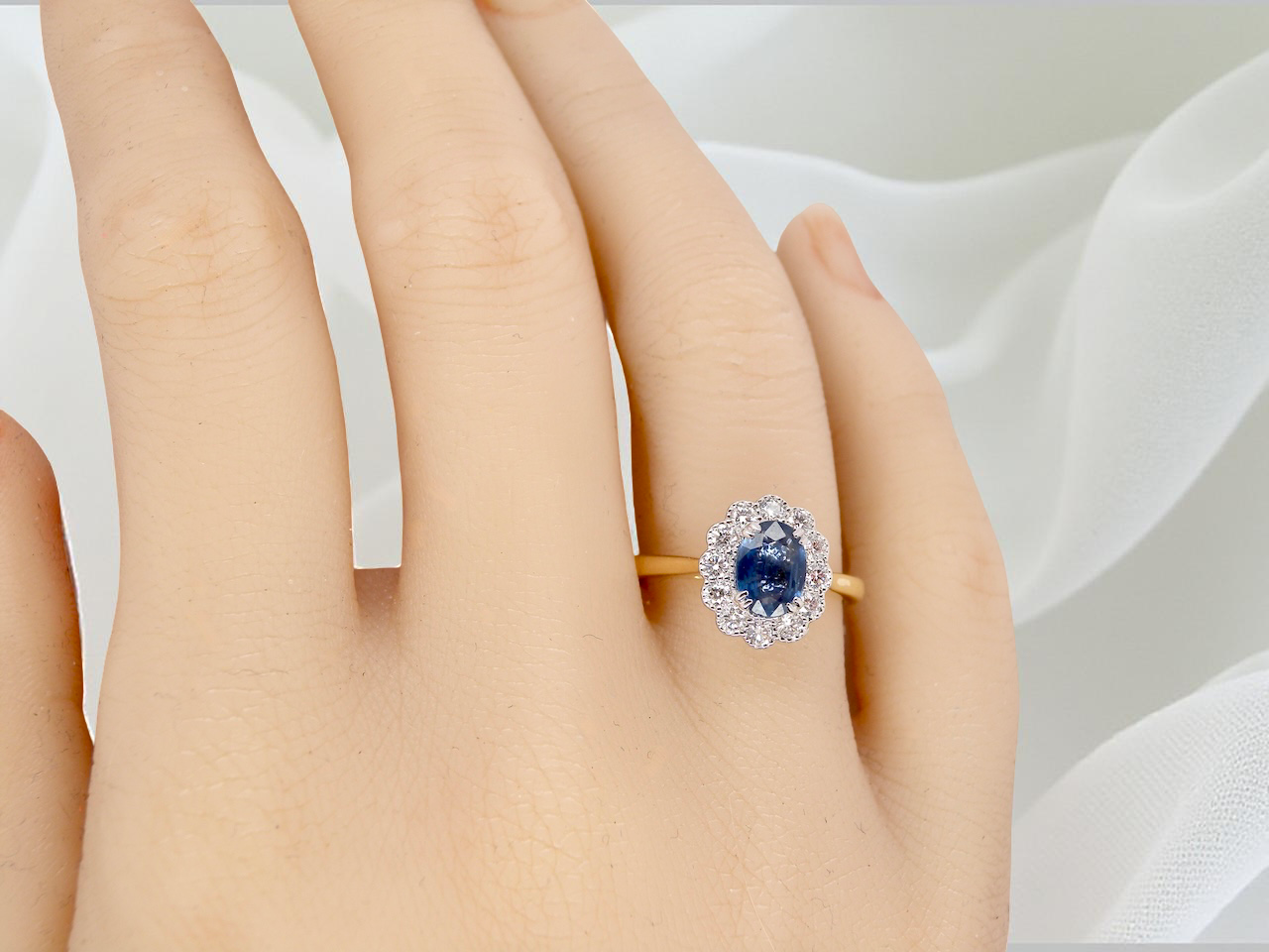 hand A beautiful cluster ring featuring an oval-cut mid to dark blue sapphire measuring 7 × 5 mm (approximately ¾ carat).