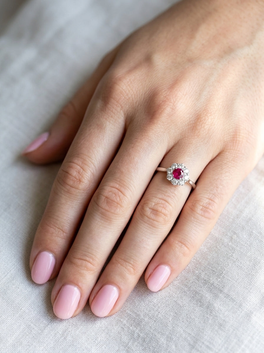hand A beautiful cluster ring set with a raspberry-red ruby centre stone measuring 5mm in diameter, estimated at approximately 0.50 carats.