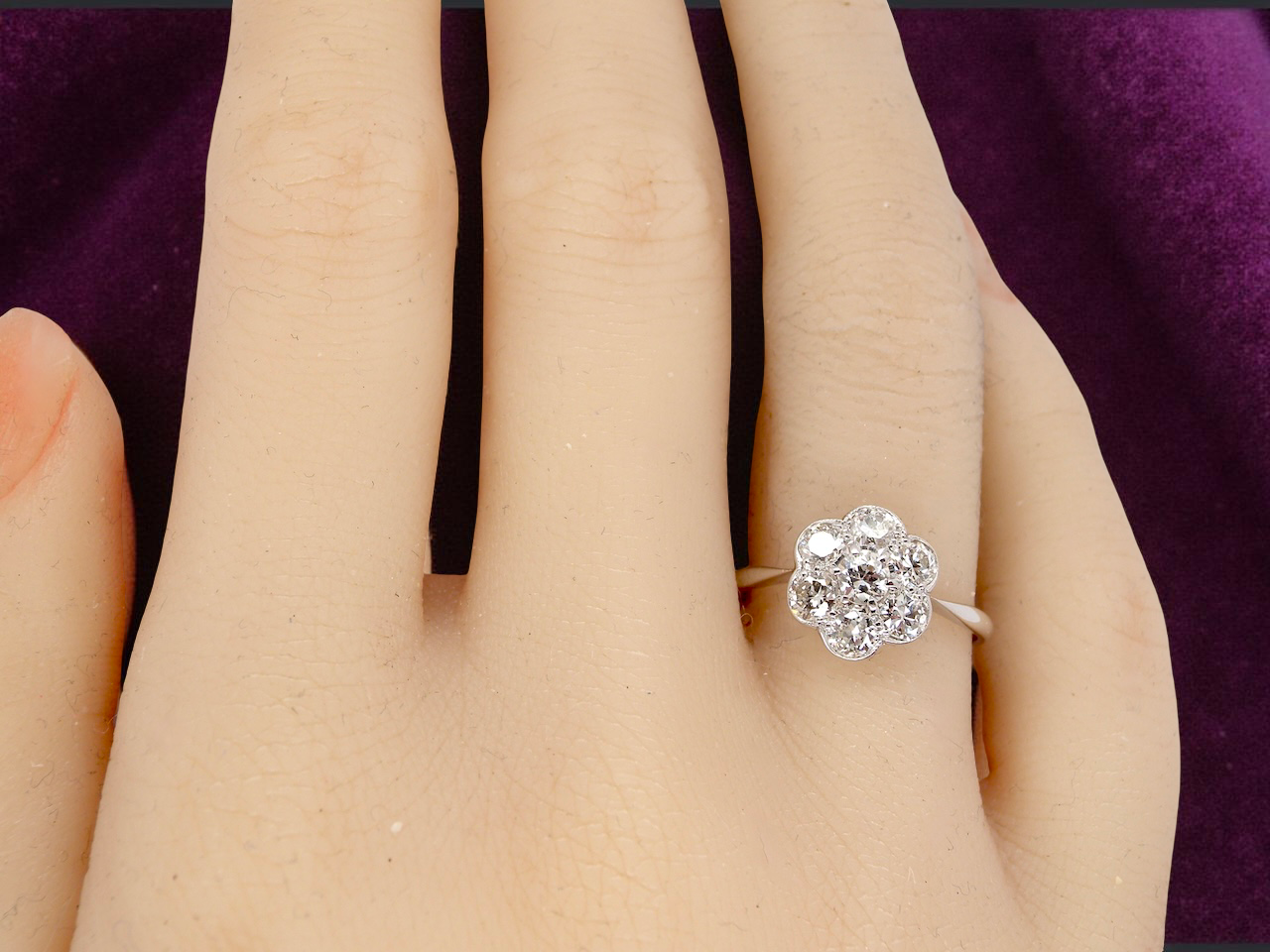 Diamond ring on a person's finger with a purple background