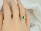 hand A beautifully elegant cluster ring featuring a central oval-cut emerald, measuring 5 x 4mm (estimated 0.40 carats).