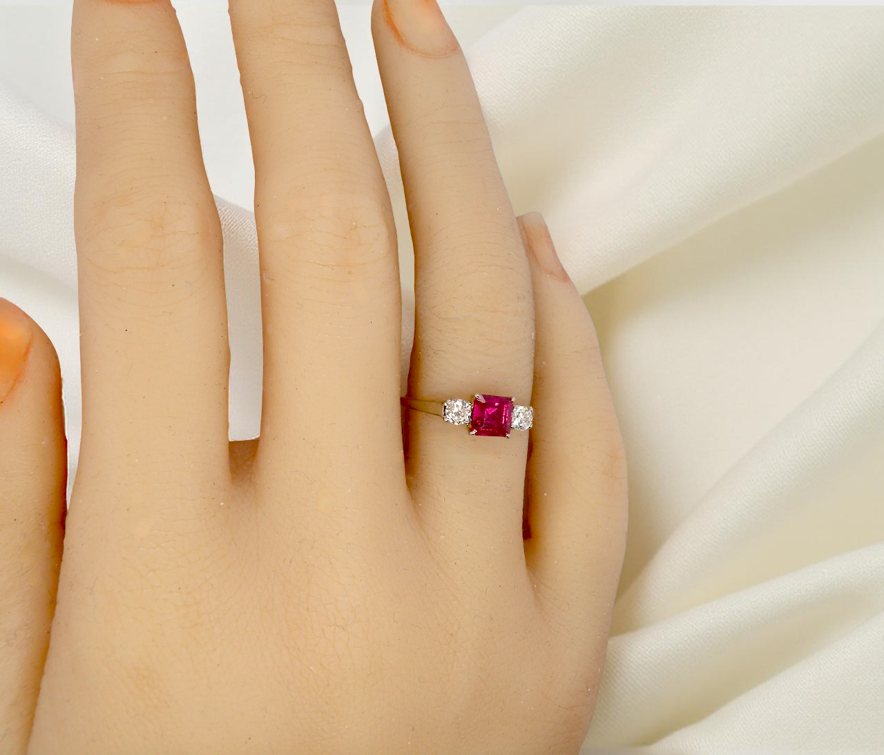 Ring with a red gemstone on a hand against a white background