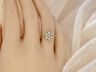 hand A daisy cluster dress ring. Set with a small diamond centre stone, diameter 3mm (0.10 carats)
