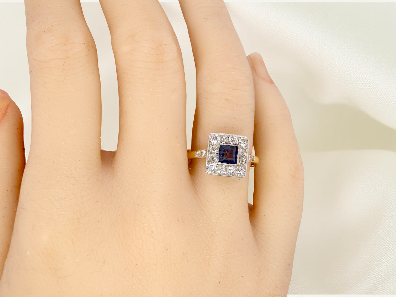 hand A fine Art Deco cluster ring. The centre stone a square sapphire 5x5mm (est 0.50 carats) in a mille grain setting.
