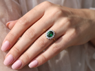 hand A fine and impressive vintage cluster ring, centred with a striking oval-cut deep dark green tourmaline, measuring 9 x 7mm and estimated to weigh approximately 2.00 carats.
