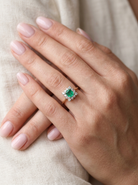hand A lovely cluster ring that features to the centre a rectangle shaped emerald, 7x5mm. Shows a deep grass green colour which does have natural inclusions common with most emeralds, but the depth of colour is impressive.