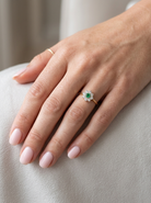 hand A pretty cluster ring that features to the centre a round emerald with diamonds