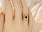 hand A rectangular cluster ring that features in its centre a cushion shaped dark blue sapphire, that measures 5x3.5mm (est 0.30 carats)