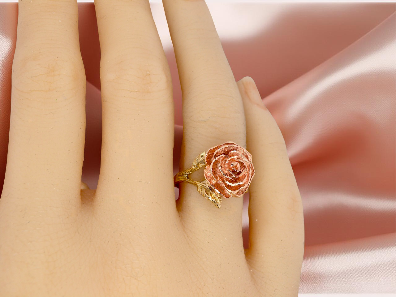 Rose gold ring on a person's finger against a soft pink background