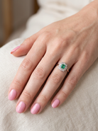 hand A vintage cluster ring, the centre stone a cushion shaped emerald 4x3.5mm, mid to dark green colour. Mille grain setting.
