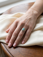 hand A vintage early 20th century cluster ring. Features to the centre a black opal doublet, with an excellent play of colour, measures 9.5x7.5mm, in a rim setting.
