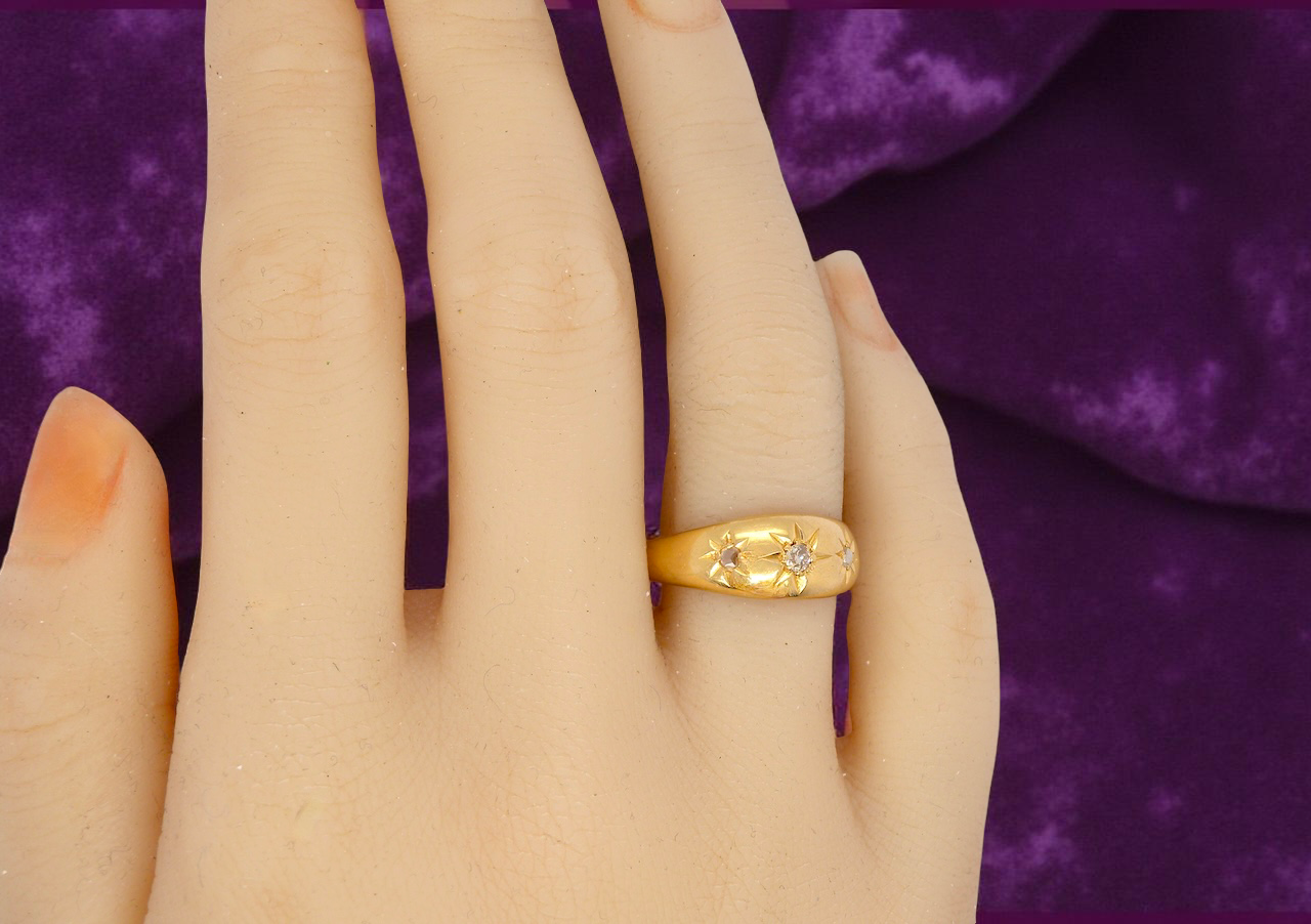Gold ring on a hand with a purple fabric background
