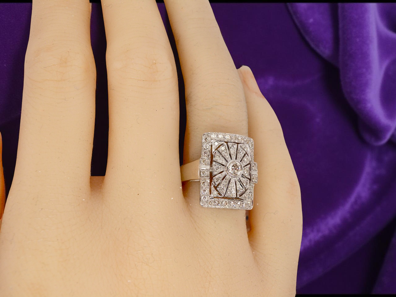 diamond ring on a hand with a purple fabric background