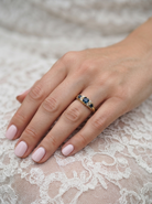 hand An 18 carat* boat shaped ring. Features three dark inky blue sapphires, centre 4.7mm, each end a 3mm stone.
