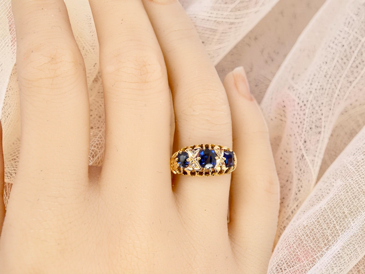 hand An 18 carat gold antique boat shaped ring. Features three oval to cushion cut sapphires, centre 6x5mm, each end 5x3mm. Mid to dark blue