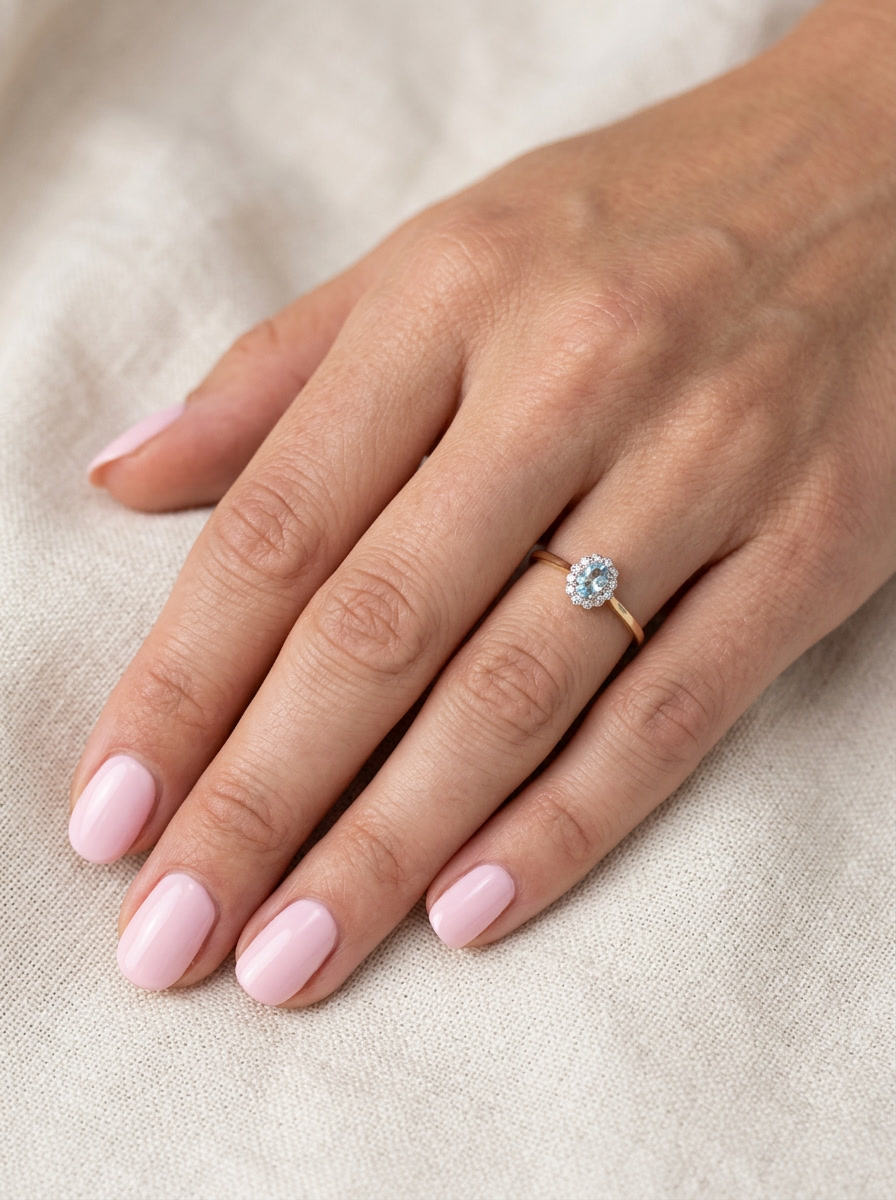 hand An 18 carat gold cluster ring. Set to the centre a lovely ice blue aquamarine 6x4mm, claw set.
