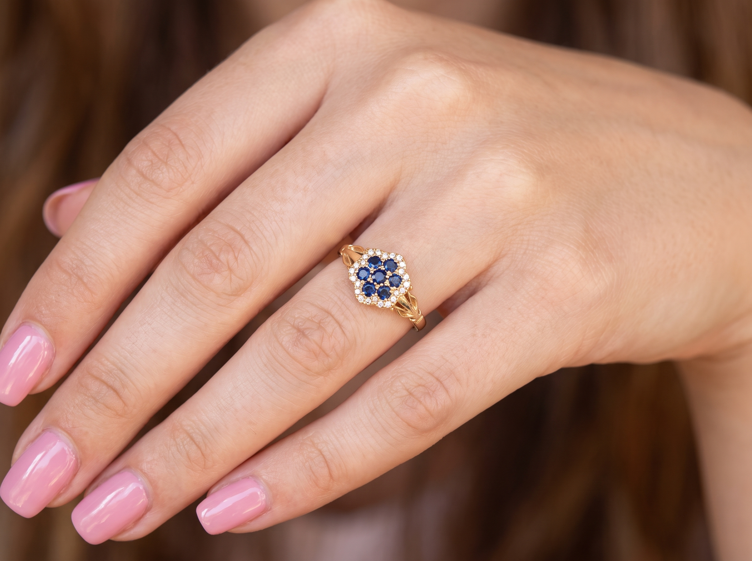 hand An 18 carat gold cluster ring.&nbsp; The centre a floral combination of seven sapphires, each 2.5mm, mid to dark blue.