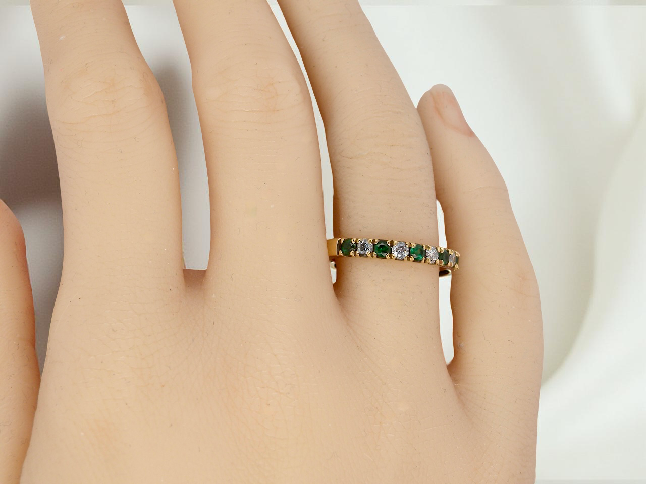hand An 18 carat gold half-hoop eternity ring, set with&nbsp;six round-cut emeralds
