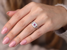 hand An 18 carat gold square cluster that features to the centre a round ruby and an outer halo of brilliant cut white diamonds.
