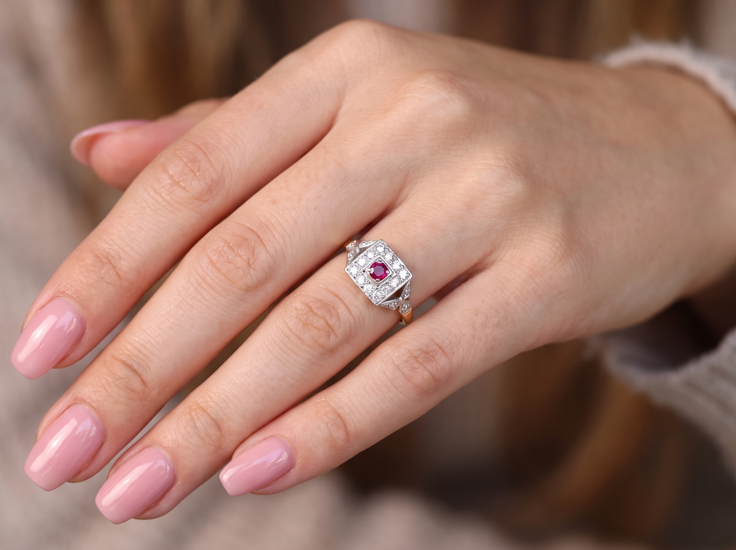 hand An 18 carat gold square cluster that features to the centre a round ruby and an outer halo of brilliant cut white diamonds.
