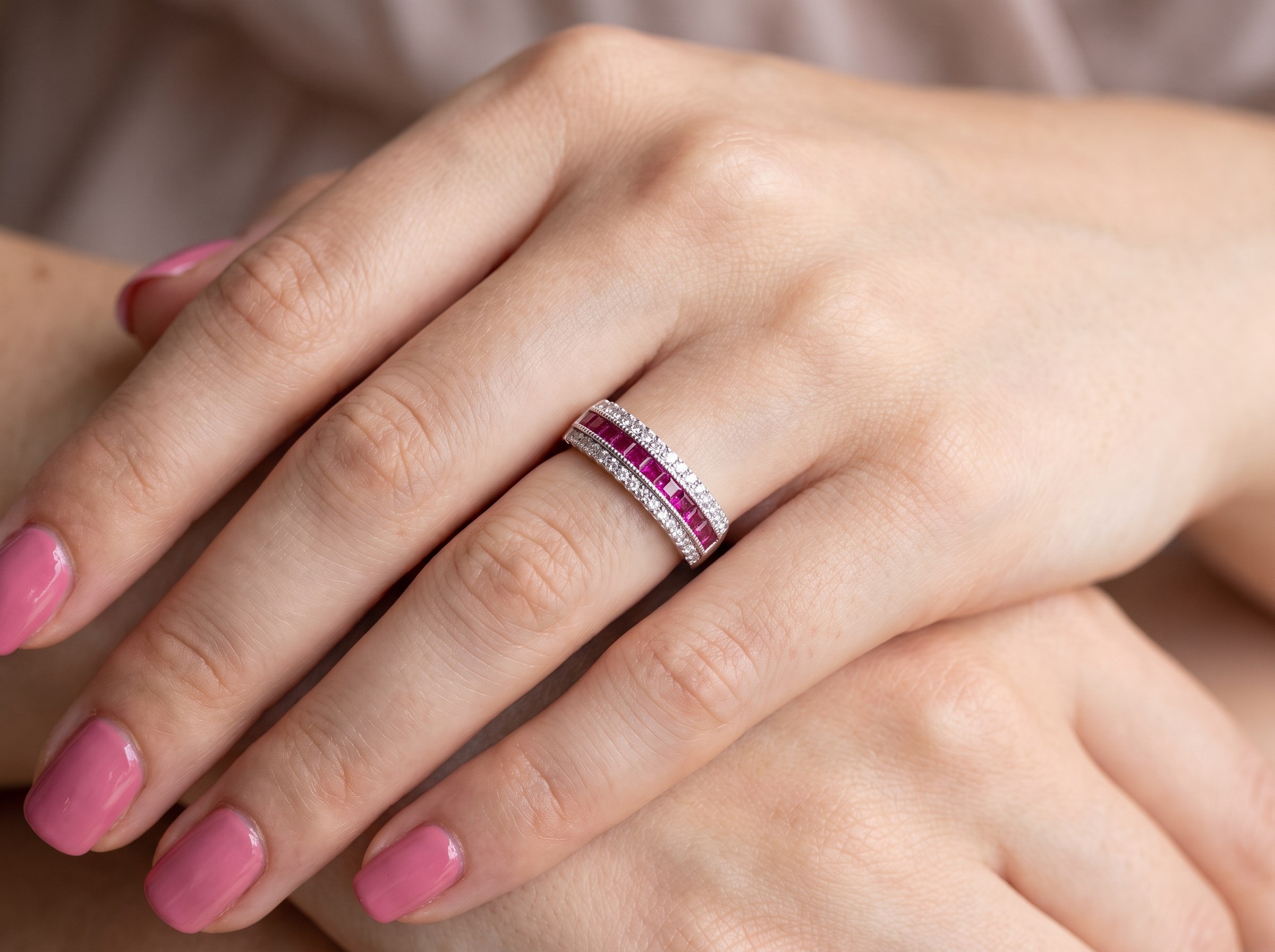 hand An 18 carat white gold half hoop ring. A triple row design with a line of channel set calibre cut rubies running along the centre , to a total carat weight of 0.97 carats.
