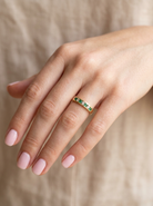 hand An 18 carat yellow gold half hoop eternity ring. Set with four round emeralds, each 3mm, and alternate set with brilliant cut white diamonds, each 3mm (total est 0.30 carats)
