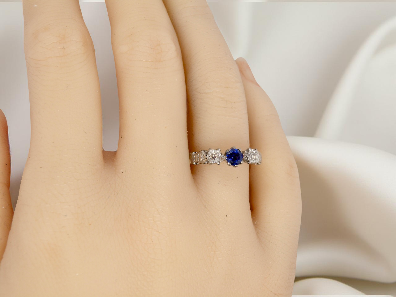 hand An early 20th century engagement ring. The centre stone a dark blue sapphire