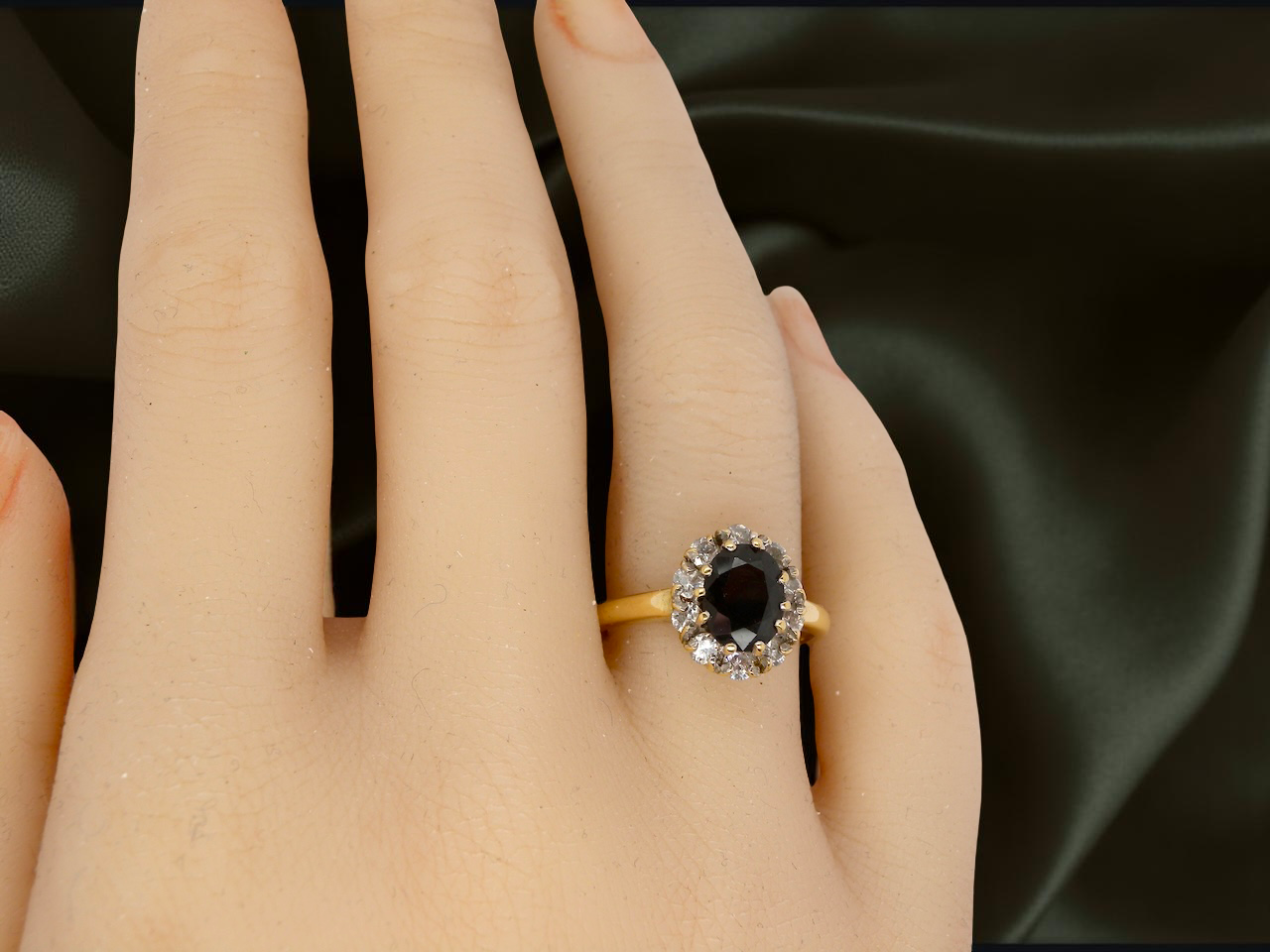 hand An elegant 18 carat gold cluster ring featuring a striking inky dark blue sapphire at its centre. 