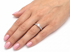 A close-up of a hand with pink manicured nails wearing a diamond engagement ring on the ring finger, set against a plain white background.