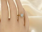 hand An elegant&nbsp; cluster ring featuring a white opal centre stone measuring 6 × 4mm, displaying a lively and attractive play of colour.