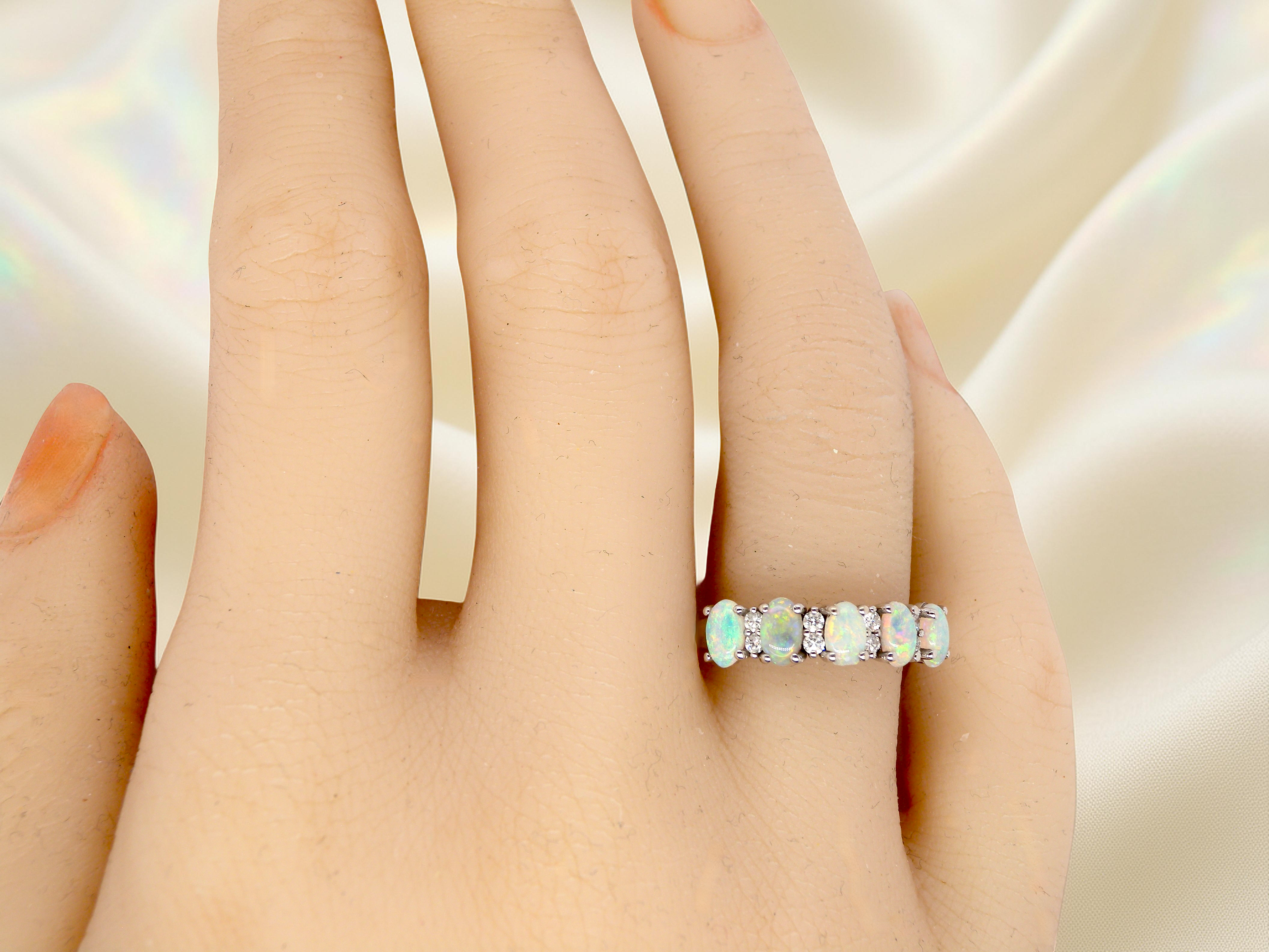 hand An elegant opal and diamond half hoop ring, featuring five oval opals with lively play of colour. Each opal measures 5 x 3mm, with an estimated total opal weight of approximately 0.75 carats, all claw set to maximise light and colour.