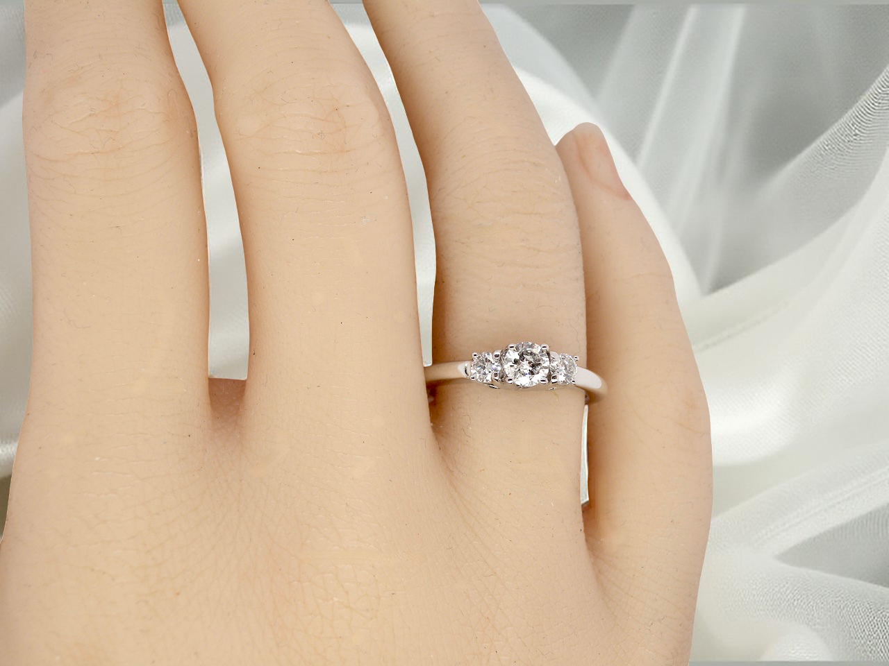 hand An elegant trilogy ring set with three brilliant-cut white diamonds, 