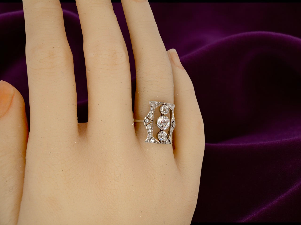 Diamond ring on a hand with a purple fabric background