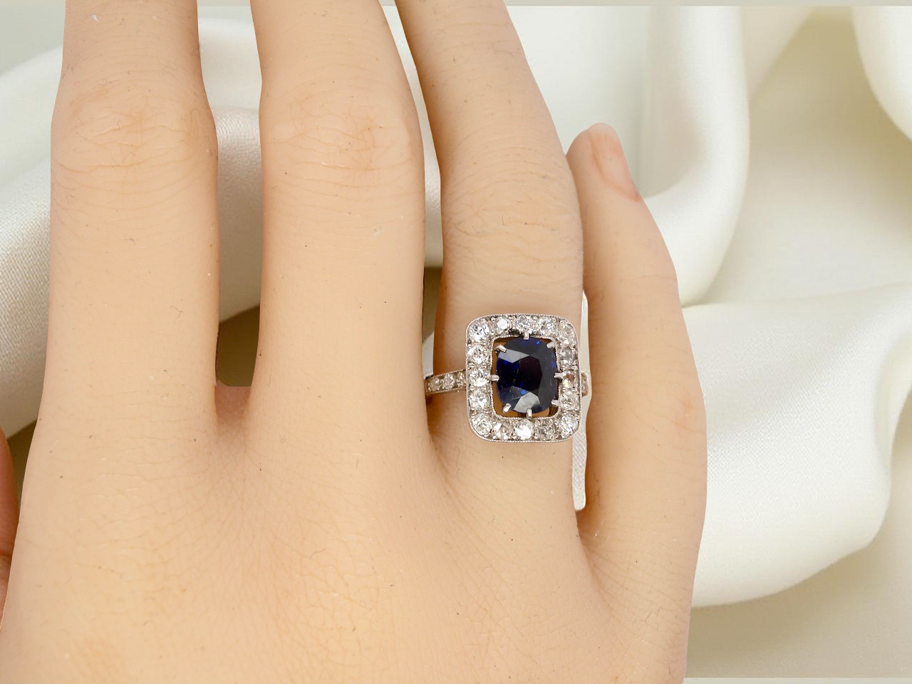 hand beautiful original Art Deco cluster ring featuring a rich, dark blue oval-cut sapphire