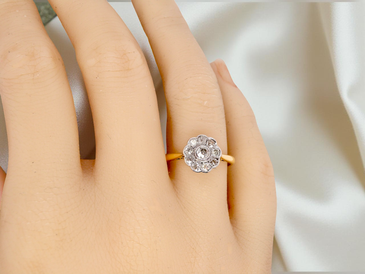 hand early 20th-century vintage diamond cluster ring, featuring a classic daisy-shaped head set with nine old brilliant-cut white diamonds.