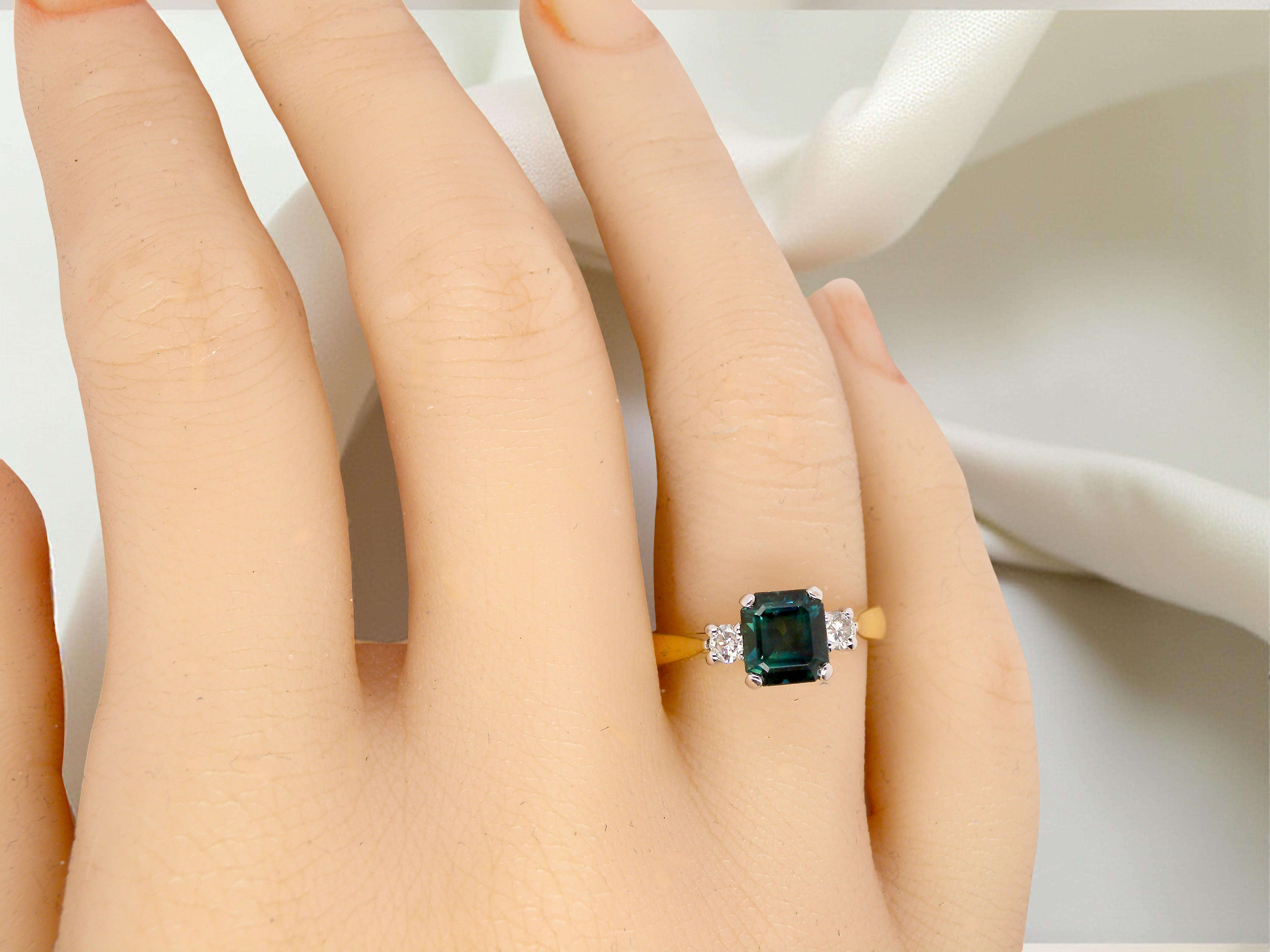 hand elegant 18 carat yellow gold trilogy ring featuring a striking natural sapphire at its centre