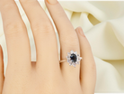 hand  fine 18 carat white gold cluster ring. Features an oval cut dark blue sapphire centre stone 