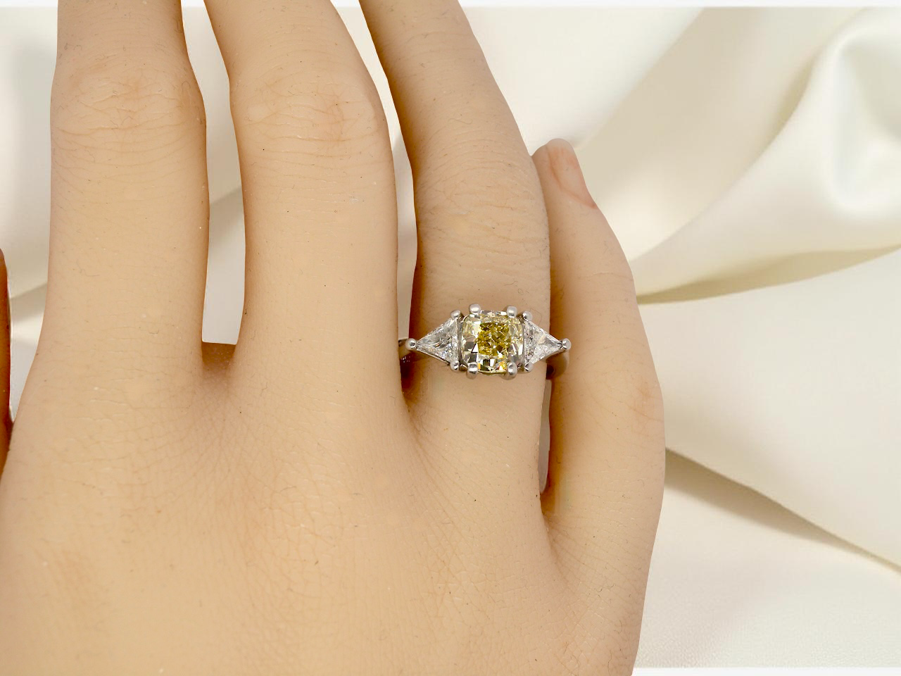 hand striking and elegant trilogy ring crafted in 18-carat white gold, set with a vibrant fancy yellow cushion-cut diamond