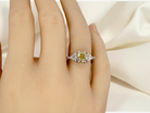 hand striking and elegant trilogy ring crafted in 18-carat white gold, set with a vibrant fancy yellow cushion-cut diamond