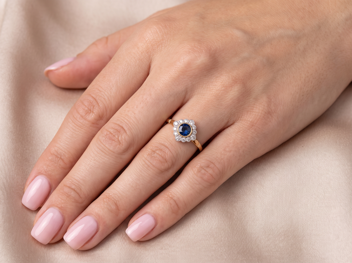 model A fine cluster ring featuring to the centre a round dark blue sapphire, 5mm diameter (0.50 carats) mille grain setting.

