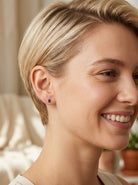 model A pair of 18 carat gold earrings*. Set with a dark blue oval cut sapphire 6x4mm, claw set.

Above each, three small white diamonds, overall size 9x4.6mm, weight each 1 gram.
