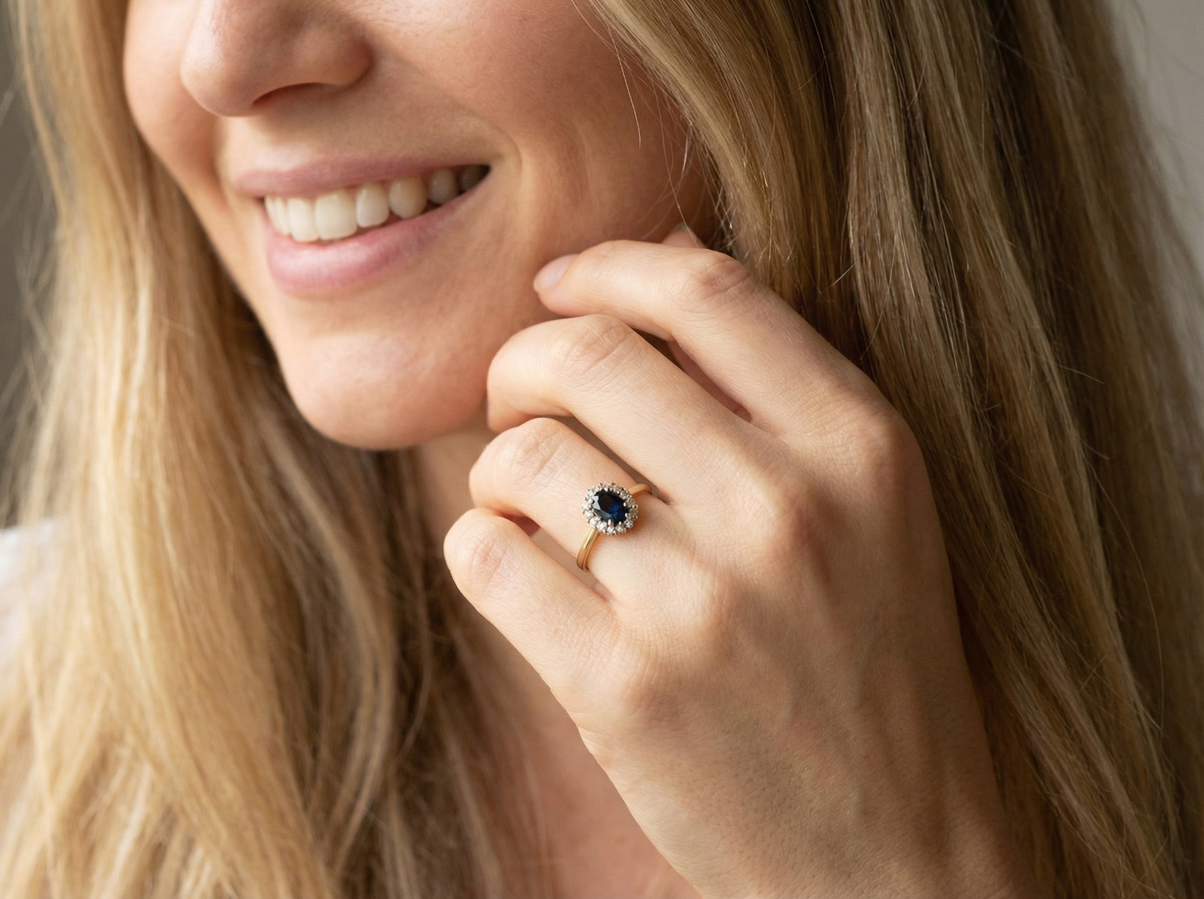 modelAn elegant 18 carat gold cluster ring featuring a striking inky dark blue sapphire at its centre. 
