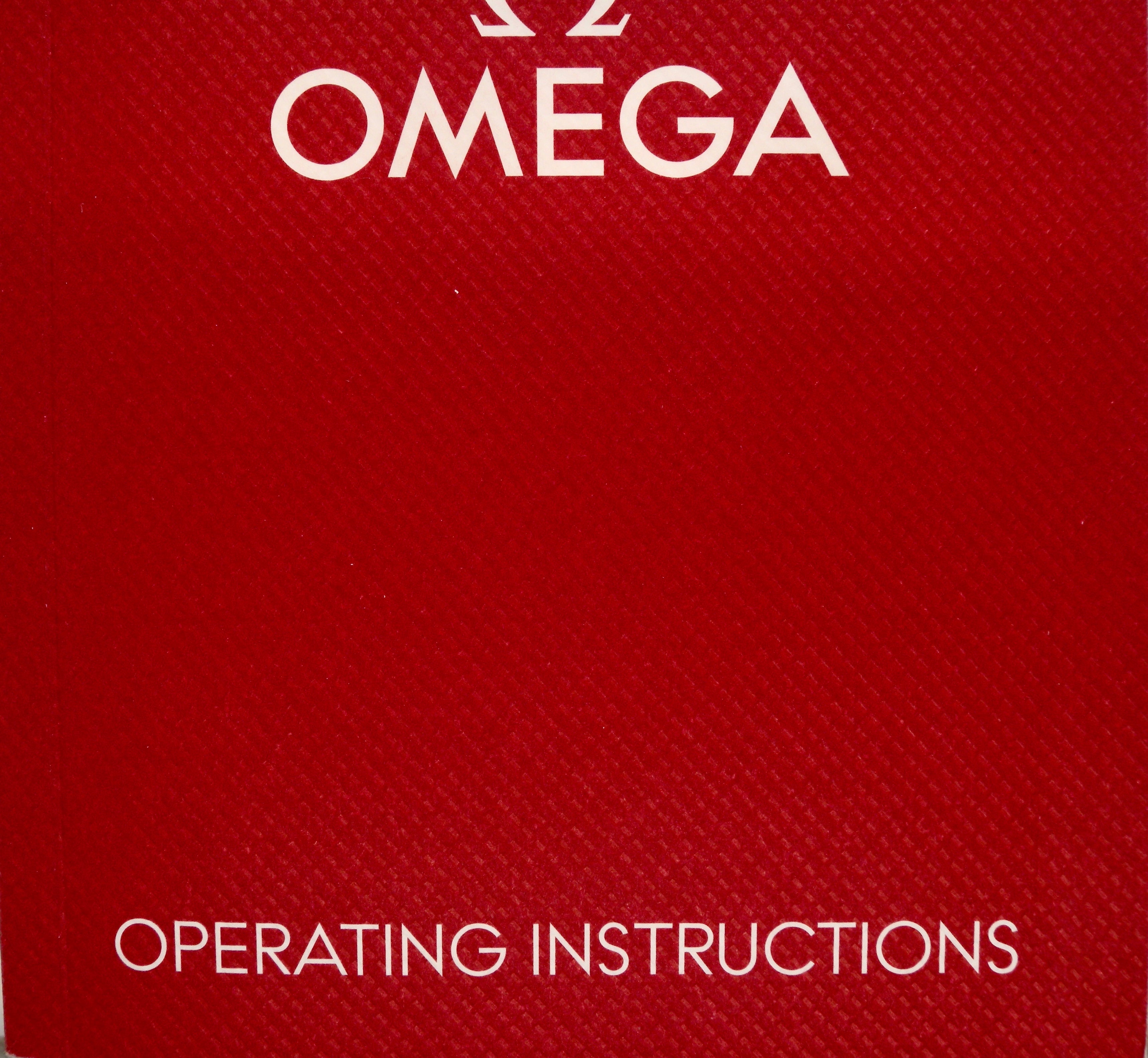 A close-up of a red textured Omega box or booklet cover with the word OMEGA at the top and OPERATING INSTRUCTIONS at the bottom in white text.