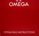 A close-up of a red textured Omega box or booklet cover with the word OMEGA at the top and OPERATING INSTRUCTIONS at the bottom in white text.
