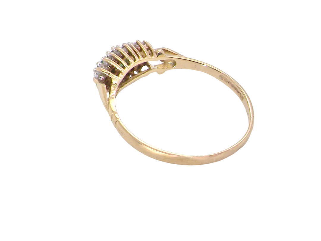 rear A 9 carat gold cluster ring. Set to the centre three round emeralds, centre 3.2mm, each side a 2.6mm stone.