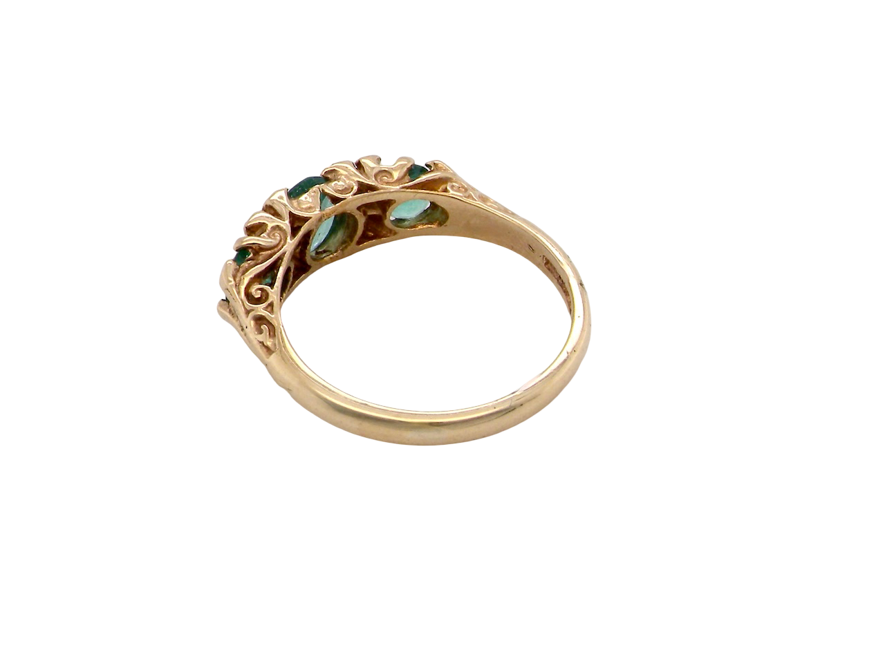 Gold ring with green gemstones on a white background