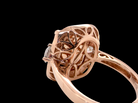 Rose gold filigree ring with a diamond cluster setting, shown in a close-up side profile against a solid black background.