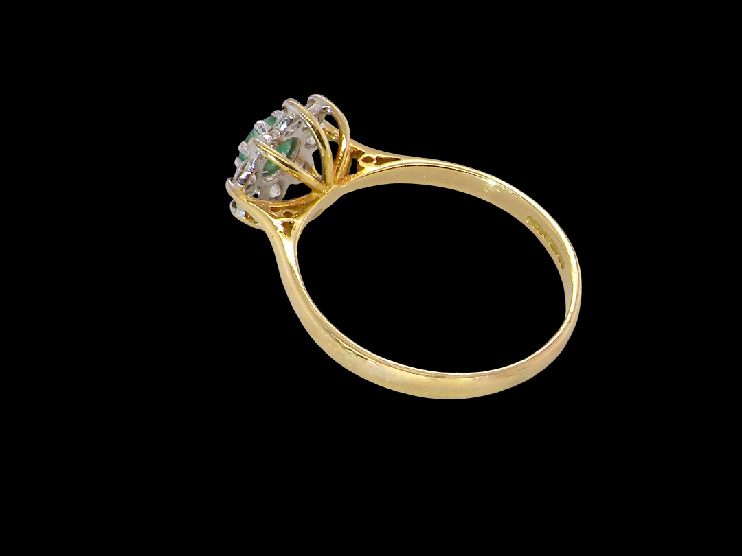 rear A pretty 18 carat gold cluster ring. The centre stone is a round emerald 4mm diameter (0.25 carats) mid green colour.
