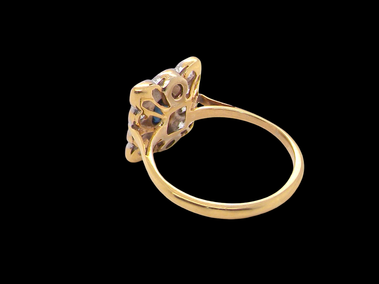 rear A rectangular cluster ring that features in its centre a cushion shaped dark blue sapphire, that measures 5x3.5mm (est 0.30 carats)