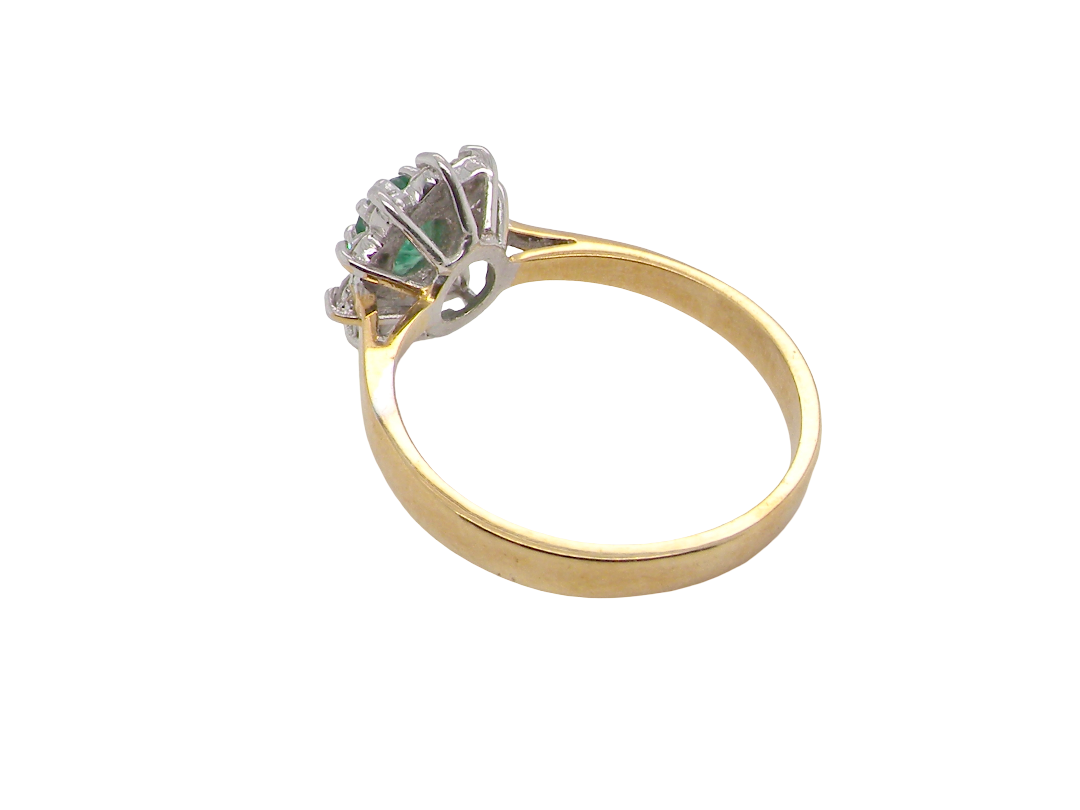 rear A traditional cluster ring. Features to the centre an oval shaped emerald, 5.5x4.5mm (est 0.35 carats) deep green colour.&nbsp;