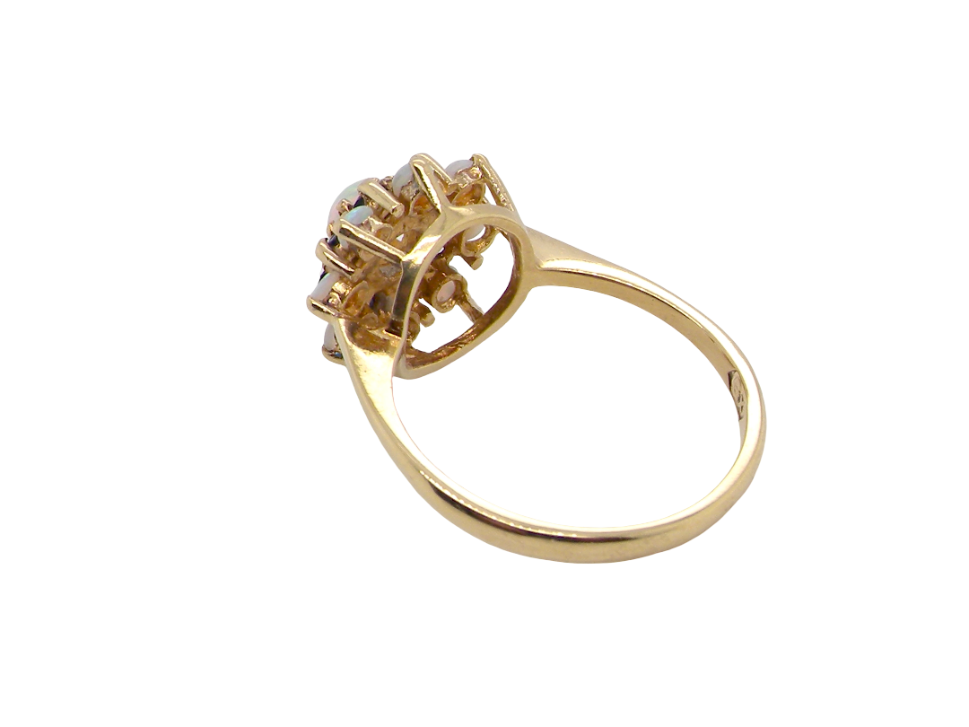 rear An 18 carat gold cluster dress ring. Features top the centre a white opal 4.7mm diameter, surrounded by an inner halo of eight 2mm sapphires, then an outer halo of eight 2.2mm opals.
